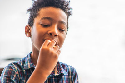 Boy with eyes closed eating food