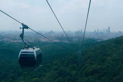 Overhead cable car over city against sky