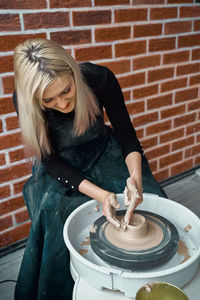 High angle view of woman molding clay on pottery wheel