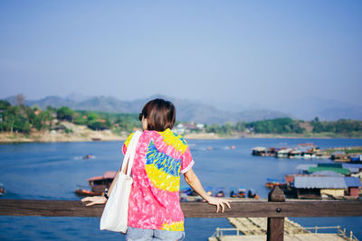 Rear view of woman standing at beach against sky