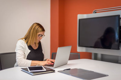 Woman using mobile phone while sitting on table