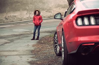 Full length portrait of young woman standing on road