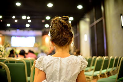 Rear view of girl standing against illuminated ceiling