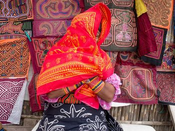 Woman covering face with red towel in market