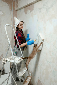 Girl painter paints the walls with a roller.  her cat is next to her.  funny