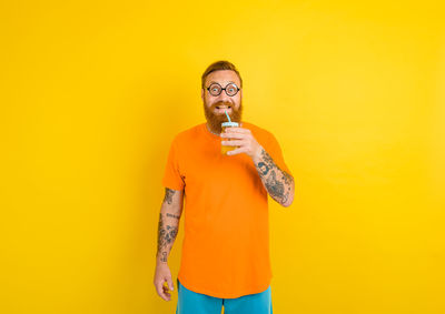Portrait of man standing against yellow background