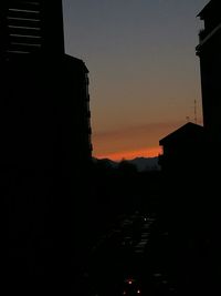 Silhouette houses against sky at sunset