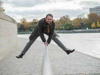 Portrait of smiling man jumping over railing