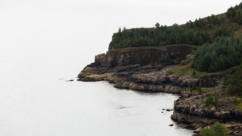 Rock formations by sea against clear sky