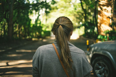 Rear view of woman with umbrella against trees in city