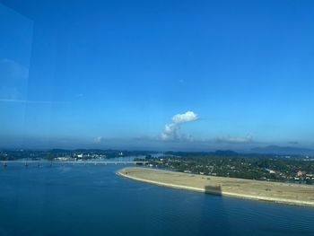 High angle view of city by sea against blue sky