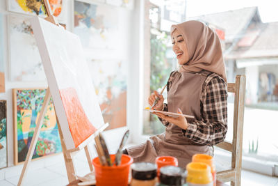 Smiling woman painting on canvas