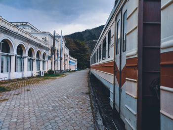 Train on street amidst buildings against sky