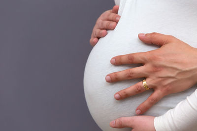 Midsection of woman touching hand against white background