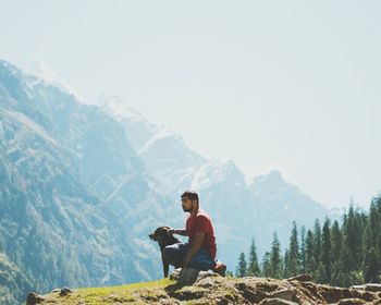 Side view of man using mobile phone against mountains