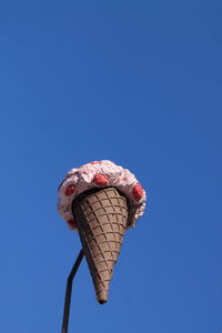 Low angle view of ice cream cone sculpture against clear blue sky