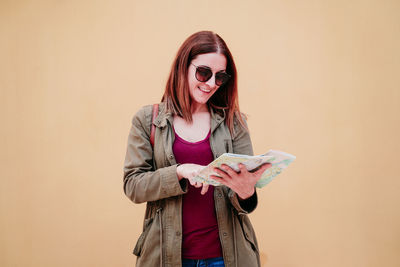 Smiling young woman standing against wall