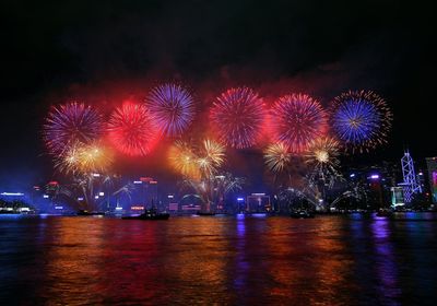 Low angle view of firework display over river against sky