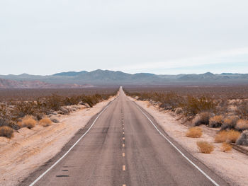 Road leading towards mountains against sky