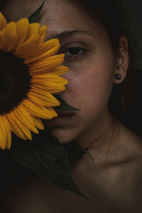 Close-up portrait of young woman with sunflower