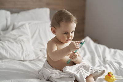 Girl holding toothbrush sitting on bed