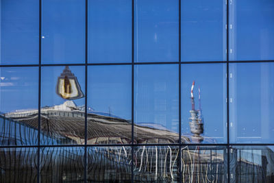 Built structure against blue sky seen through fence