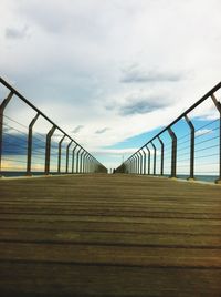 Pier on sea against cloudy sky