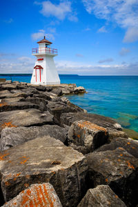 Lighthouse by sea against sky