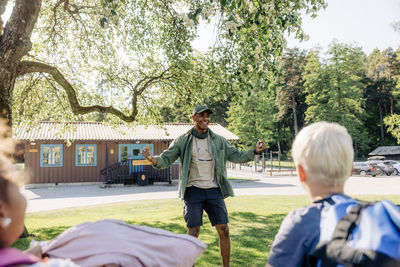 Excited male camp counselor encouraging kids at summer camp