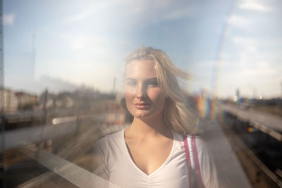 Double exposure image of young woman with railroad tracks against sky