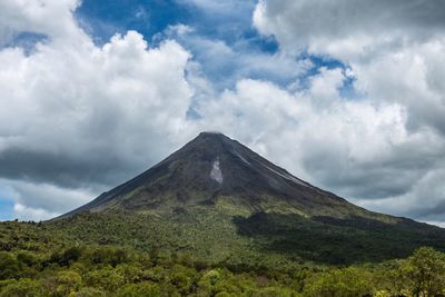 Low angle view of volcanic mountain against cloudy sky