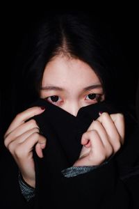 Close-up portrait of a beautiful young woman over black background