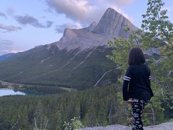 Rear view of woman standing on mountain against sky