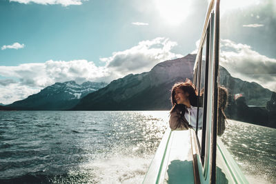 Young woman looking through ferry boat window in sea