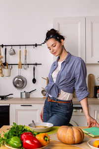 Young and beautiful housewife woman cooking in a white kitchen