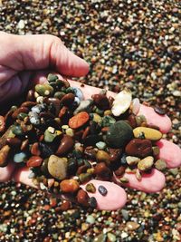 Close-up of hand holding pebbles at beach