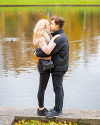 Side view of couple kissing while standing by lake