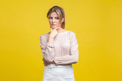 Portrait of serious young woman against yellow background