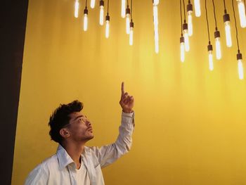 Man pointing at illuminated pendant lights in home
