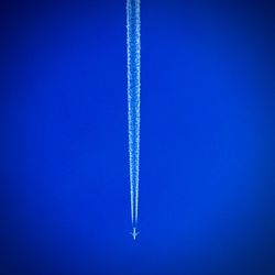 Low angle view of vapor trails in blue sky