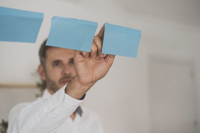 Businessman sticking blank adhesive note on glass