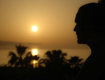 Silhouette woman against sea at sunset