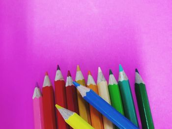 High angle view of multi colored pencils against pink background