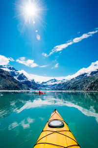 Scenic view of lake and snowcapped mountains against blue sky