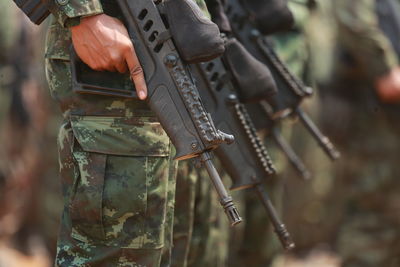 Midsection of army soldiers holding rifles