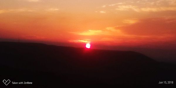 Scenic view of silhouette mountain against orange sky