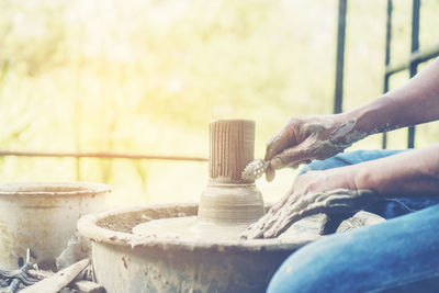 Cropped image of man making pot outdoors