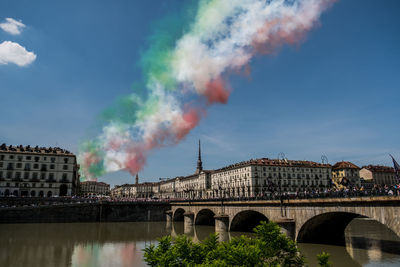 Bridge over river against sky in city