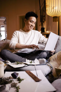 Smiling man using laptop on sofa in living room at home