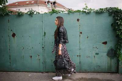 Young woman in dress and leather jacket walking around town